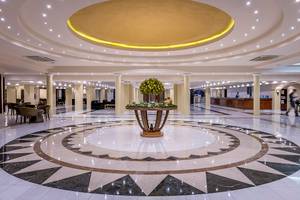 Die geräumige Lobby des Mitsis Grand Hotel Beach mit einer zentralen Blumeninstallation und gemustertem Boden.