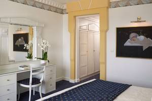 Innenansicht eines Zimmers im Mitsis Grand Hotel Beach mit Bett, Schreibtisch und Spiegel.