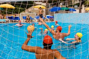 Gruppe von Männern und Frauen spielt Wasserball im Pool des Fantasia Hotel De Luxe