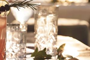 Cocktail im Glas mit Rosmarin und Limette auf einem Tisch