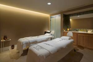 Behandlungsraum im H10 Atlantic Sunset Spa mit zwei Massageliegen und einem Spiegel.