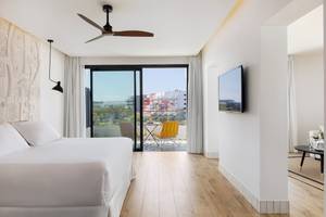 Innenansicht eines Zimmers im H10 Atlantic Sunset Hotel mit Bett, Tisch, Stühlen und Terrassenblick.
