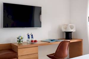 Arbeitsbereich des Zimmers im H10 Atlantic Sunset Hotel mit Fernseher, Schreibtisch, Apfel und Lampe.