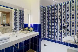Badezimmer im H10 Atlantic Sunset Hotel mit blauen und weißen Kacheln und einer Dusche