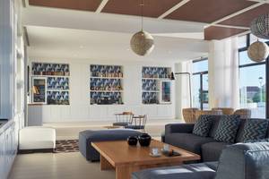 Innenbereich des H10 Atlantic Sunset Hotels mit Loungebereich, Sofas, Couchtisch und Bücherregalen.