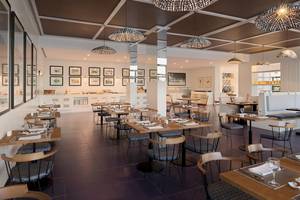 Innenansicht des Restaurants des H10 Atlantic Sunset Hotels mit Tisch und Stühlen, Tischdecken, Weinläsern und dekorativen Bildern an der Wand.