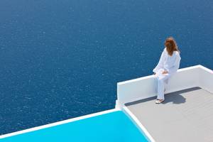 Frau auf der Terrasse von Katikies Chromata Santorini mit Blick auf das Meer