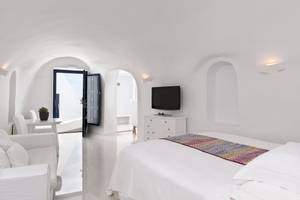 Innenansicht des Schlafzimmers im Katikies Chromata Santorini Hotel mit weißen Möbeln und einer modernen Einrichtung.