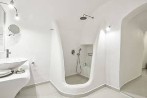 Ein Badezimmer im Katikies Chromata Santorini Hotel mit weißen Wänden und Boden.