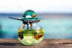 Parfumflasche mit blauem Deckel auf einem Holztisch am Strand des Nova Maldives