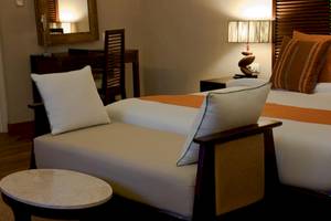 Ein Schlafzimmer im Nova Maldives Hotel mit zwei Betten, einem Nachttisch, einem Schreibtisch und einem Stuhl.