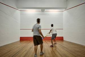 Zwei Männer spielen Badminton in einem gut beleuchteten, quadratischen Raum im Grecian Bay Hotel.