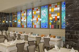 Das elegante Restaurant des Royal Seginus Hotels mit bunten Glasfenstern und gedeckten Tischen.