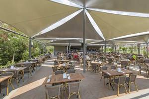 Outdoor-Restaurant im Royal Seginus Hotel mit vielen Gästen unter Sonnensegeln.