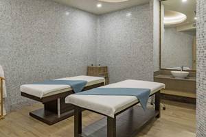 Behandlungsraum im Royal Seginus Hotel mit zwei Massagetischen und einem Bademantelhaken.