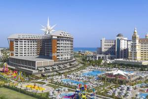 Luftaufnahme des Royal Seginus Hotels mit Swimmingpools und Spielplatz im Vordergrund.