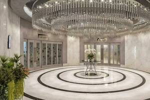 Empfangsbereich des Royal Seginus Hotels mit großem Kristallkronleuchter und moderner Inneneinrichtung.