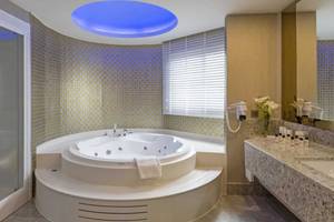 Badezimmer im Royal Seginus Hotel mit Jacuzzi und beleuchteter Decke.