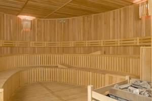 Innenbereich der Sauna im Royal Seginus Hotel mit Holzbänken und einer Lampe.