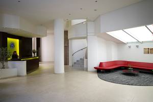 Empfangsbereich des Kriti Beach Hotel mit Rezeption, roten Sofas und zentraler Treppe.