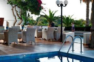 Terrasse des Kriti Beach Hotels mit Tischen, Stühlen und Swimmingpool.