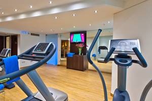 Fitnessraum im Kriti Beach Hotel mit Laufband, Fernseher und Trainingsgeräten.