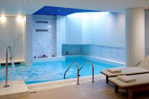 Innenpool im Kriti Beach Hotel mit weißen Marmorwänden und zwei Liegestühlen