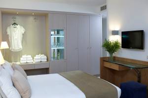 Schlafzimmer im Kriti Beach Hotel mit Bett, Kleiderschrank und Fernseher.