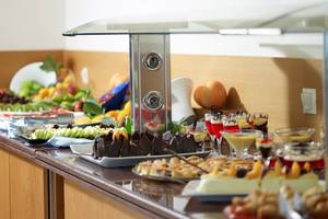 Buffet-Tisch im Kriti Beach Hotel mit einer Auswahl an Früchten, Desserts und Getränken.