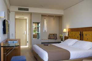 Ein elegantes Hotelzimmer im Kriti Beach Hotel mit einem großen Bett und einem Schreibtisch.