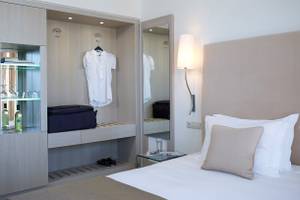 Schlafzimmer im Kriti Beach Hotel mit Bett, Kissen, Lampe und Kleiderschrank.