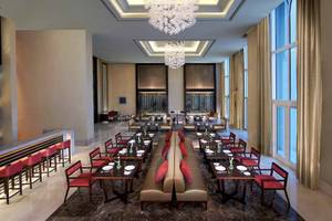 Innenbereich des Restaurants im Anantara Eastern Mangroves Abu Dhabi Hotel mit eleganten Möbeln, Kristallkronleuchtern und großen Fenstern.