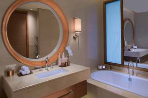 Badezimmer im Anantara Eastern Mangroves Abu Dhabi Hotel mit Badewanne, Waschbecken und Spiegeln.