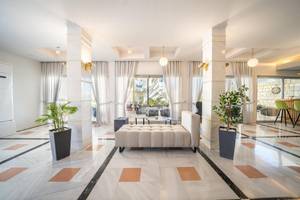 Empfangsbereich des Adele Beach Hotels mit weißem Marmorboden, hohen Säulen und modernen Möbeln.