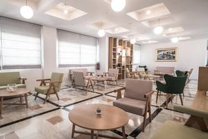 Lobby des Adele Beach Hotels mit Sitzgelegenheiten und Tischen.