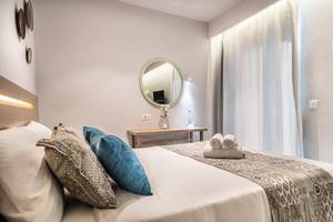 Schlafzimmer im Adele Beach Hotel mit einem Bett, Kissen, Spiegel und Nachttisch.