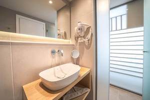 Badezimmer im Adele Beach Hotel mit Waschbecken, Spiegel und Föhn
