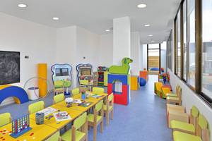 Kinderspielzimmer im NYX Ibiza Hotel mit bunten Möbeln, Spielgeräten und einer Tafel.