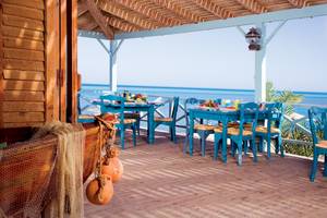 Terrasse des Mövenpick Resort & Spa El Gouna mit blauen Tischen und Stühlen und Blick auf das Meer.