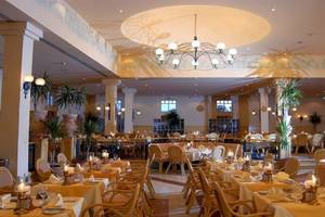 Restaurant im Mövenpick Resort & Spa El Gouna mit gedeckten Tischen, Stühlen, Kronleuchtern und Pflanzen.