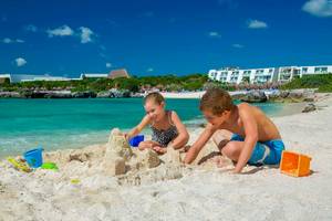 Zwei Kinder bauen am Strand des Grand Sirenis Riviera Maya Resorts und Spa einen Sandburg