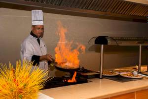 Koch im Roc Barlovento Hotel brät Speisen in einer Pfanne mit Flammen