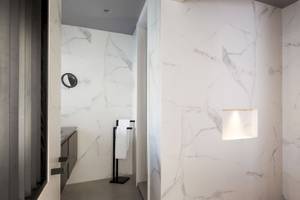 Ein Badezimmer im Kivotos Mykonos Hotel mit weißen Marmorwänden und einer eingebauten Dusche.