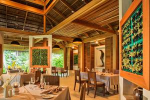 Innenbereich des Kuramathi Maldives Hotel mit Esstischen und hängenden Lampen.