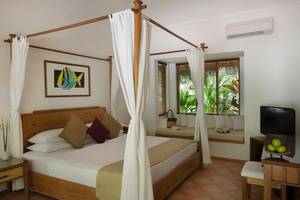 Schlafzimmer im Kuramathi Maldives Hotel mit Himmelbett, Fenstern und Klimaanlage.