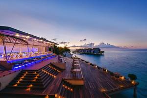 Außenterrasse des Kuramathi Maldives Hotels bei Sonnenuntergang mit Blick auf das Meer.