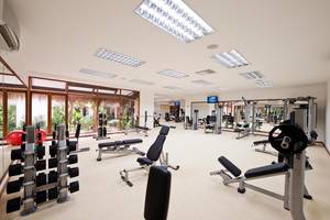 Fitnesscenter im Kuramathi Maldives Hotel mit vielen Geräten und großen Fenstern.