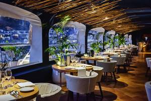 Innenansicht des Restaurants im Grand Hotel Poltu Quatu mit runden Tischen und Stühlen.