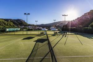 Tennisplatz des Grand Hotel Poltu Quatu mit grünem Spielfeld und Sonnenschein.