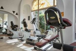 Fitnessstudio im Grand Hotel Poltu Quatu mit Technogym-Geräten und Glasfenstern